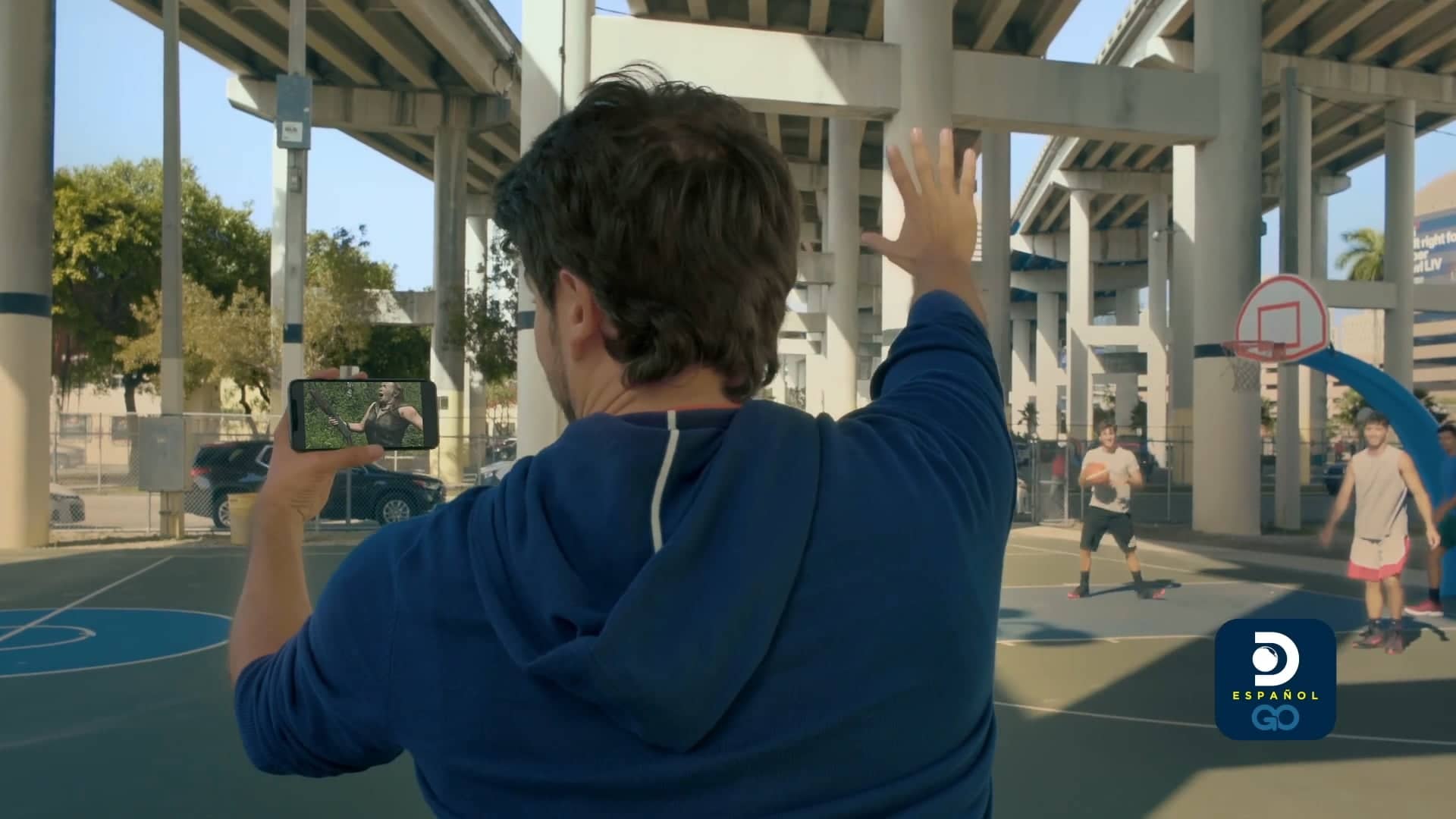 Main character of Discovery GO spot using the app while he is playing basketball