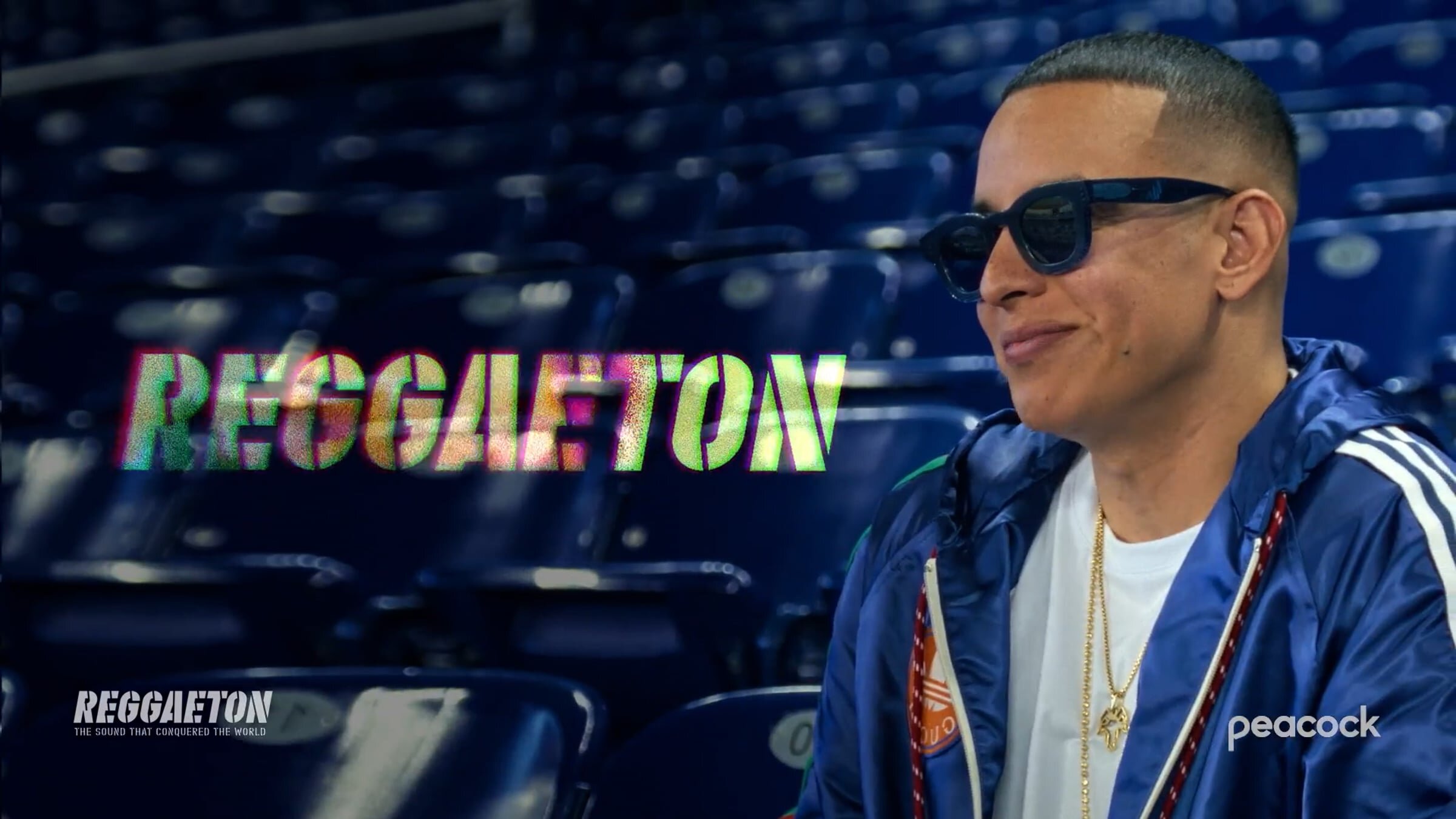 Daddy Yankee sitting in the stands looks to the side